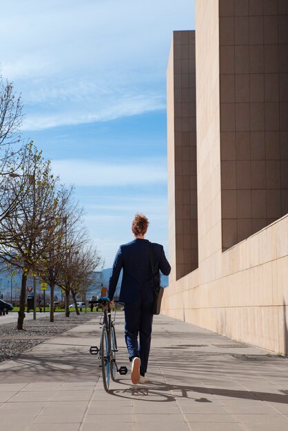 Man in suit with bicycle going to job full shot