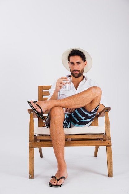 L'uomo in estate indossa sulla sedia con un bicchiere d'acqua