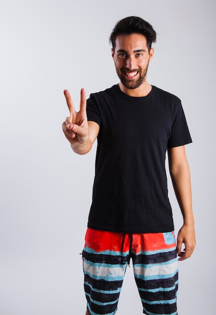 Free photo man in summer wear making peace sign