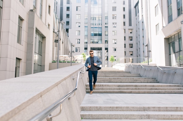 Free photo man in sunglasses runningg on concrete stairs