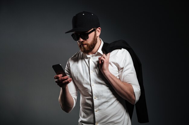 Man in sunglasses and shirt holding phone and looking away