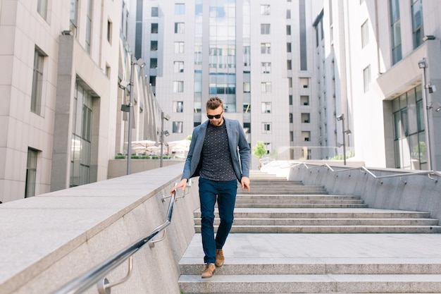 Man in sunglasses walking on concrete stairs