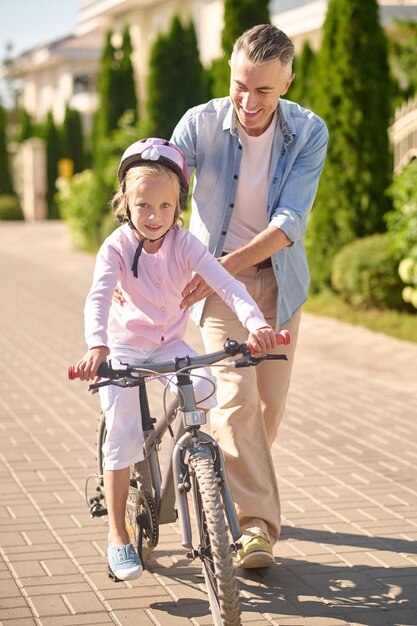 自転車に乗っている女の子を支える男