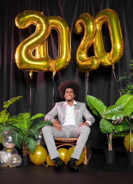 Man surrounded by happy new year 2020 balloons