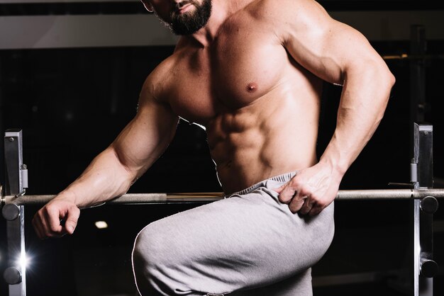 Man in sweatpants posing near barbell