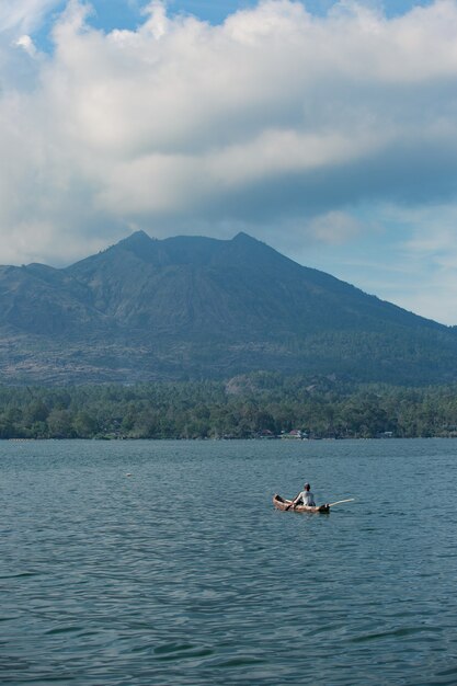 Man swims in a boat overlooking the volcano.