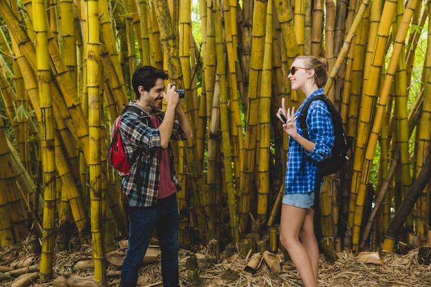 Free photo man takes photo of girlfriend in bamboo forest