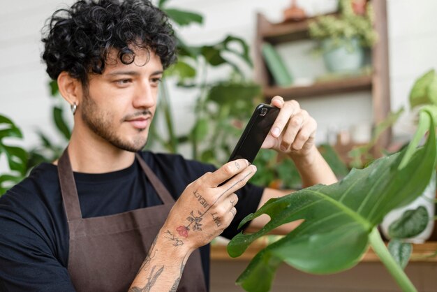 Мужчина фотографирует комнатное растение, чтобы поделиться в социальных сетях