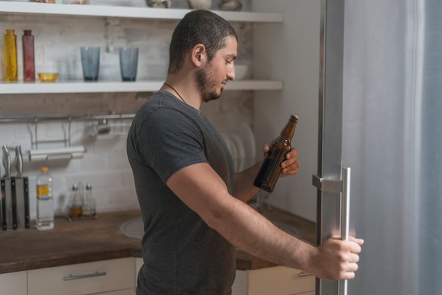 冷蔵庫からビールを飲む男