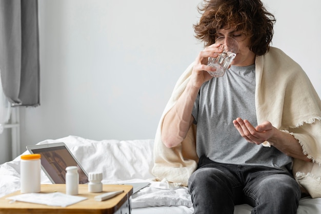 Man taking his pills in bed