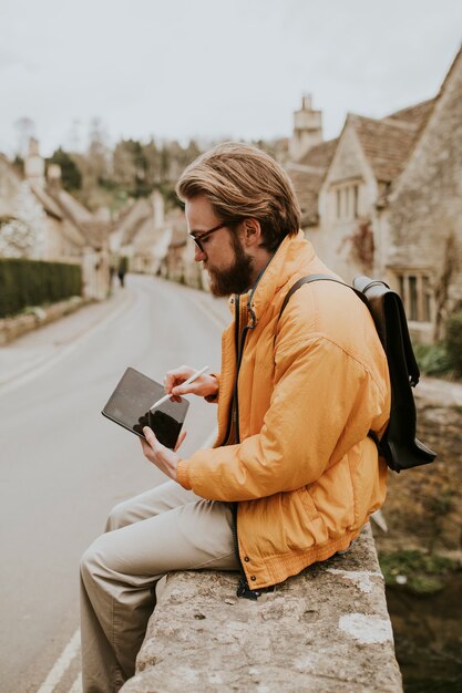 英国コッツウォルズ村でタブレットにメモを取っている男性