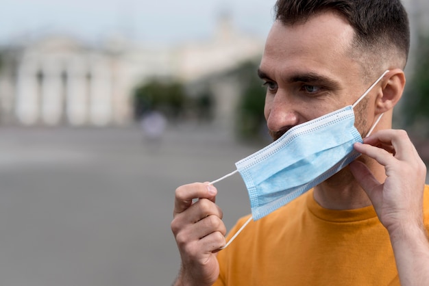 Бесплатное фото Мужчина снимает медицинскую маску на открытом воздухе