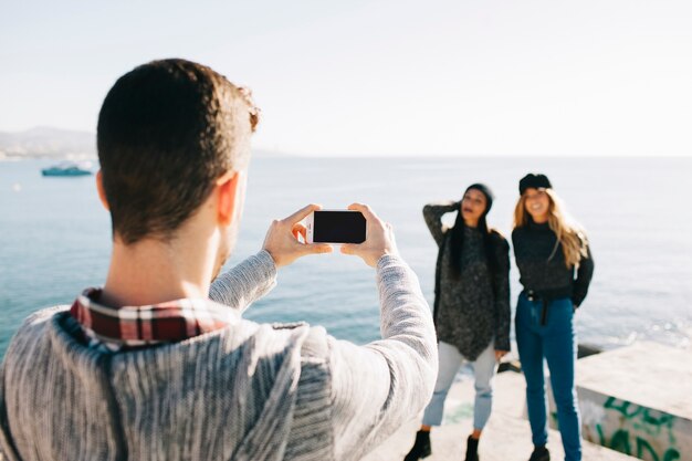 Man taking photo of girls in front of sea