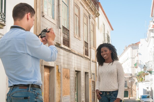 Man taking photo of happy black woman outdoors