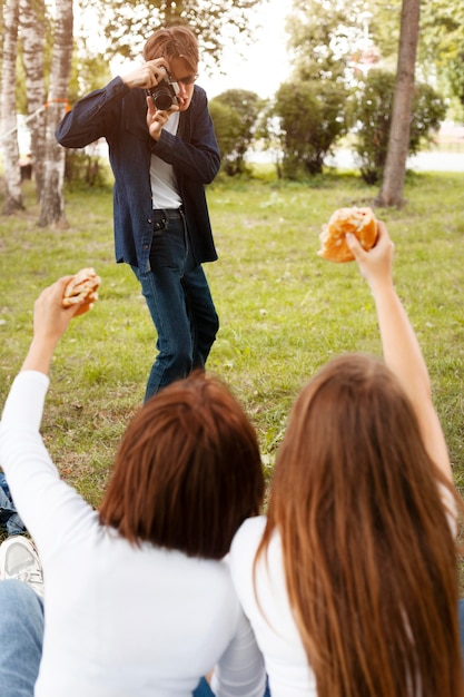 Man taking photo of his friends while they hold burgers