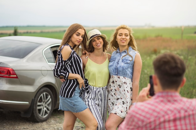 無料写真 車の近くに立っている3人の女性の友人の写真を撮っている男