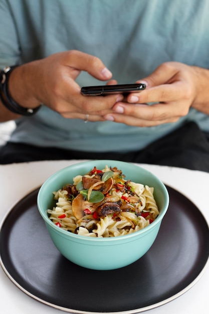 Man taking photo of pasta bowl with smartphone