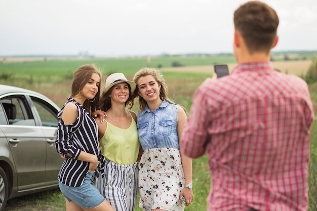 Man taking photo of three female friends on mobile phone