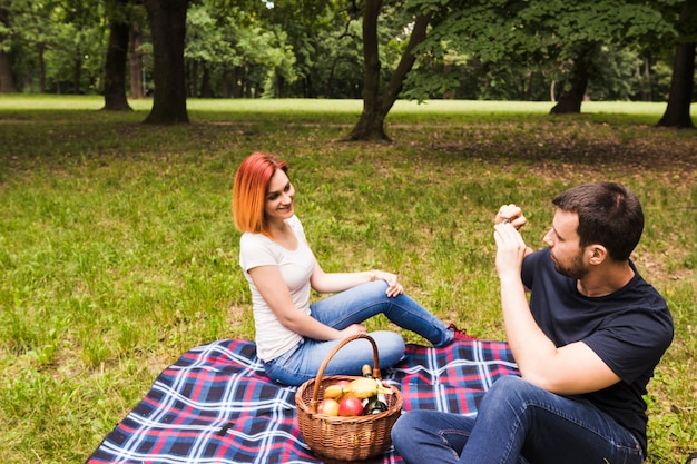 Man taking photograph of her girlfriend on cell phone at picnic