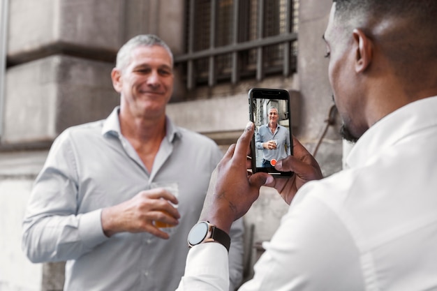 Foto gratuita uomo che scatta foto di un amico con lo smartphone