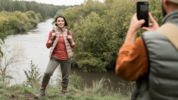 Man taking photos of girlfriend in nature with smartphone