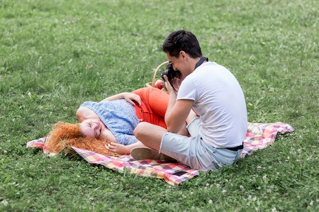 Человек принимает фотографии своей подруги на траве