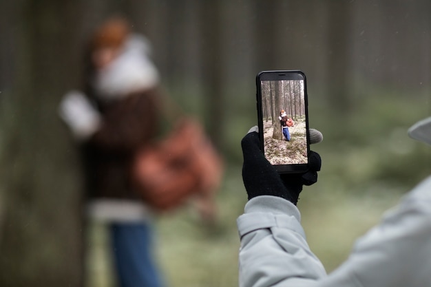 Man taking pictures of woman while on winter road trip in the forest