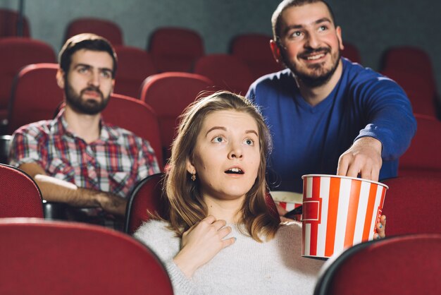 Человек, принимающий попкорн от женщины в кино