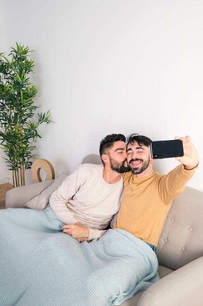 그의 남자 친구가 키스하는 동안 휴대 전화에 자기 초상화를 복용하는 사람