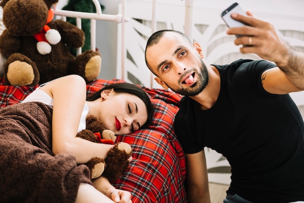 Free photo man taking selfie near sleeping woman