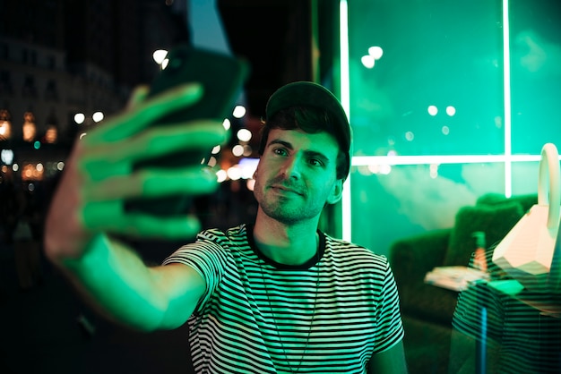 Free photo man taking a selfie in the night