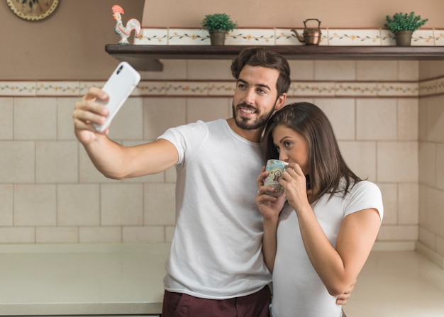 Man taking selfie with drinking girlfriend