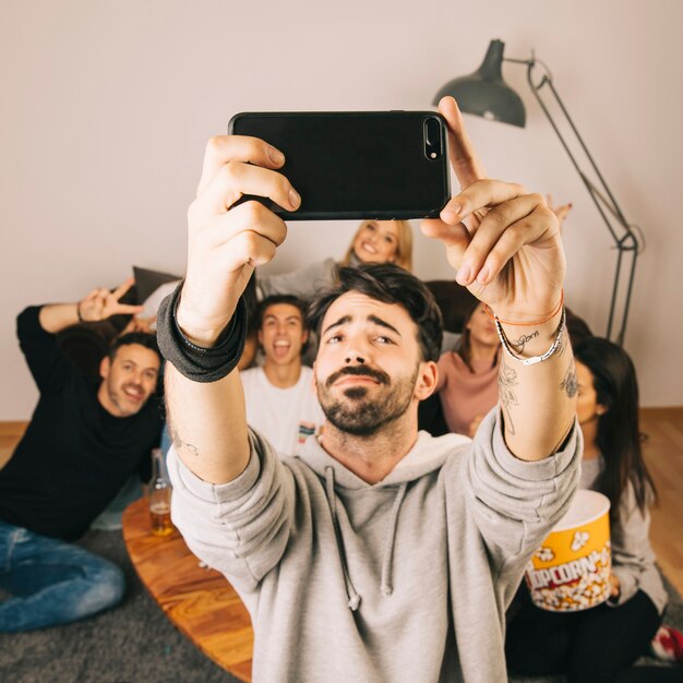 Man taking selfie with friends in living room