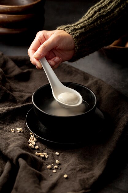 Man taking a spoon of soup from a black bowl