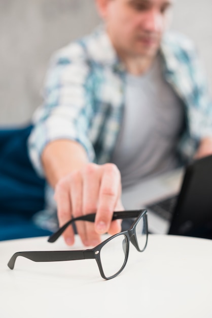 Man taking stylish glasses from table 