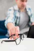 Free photo man taking stylish glasses from table