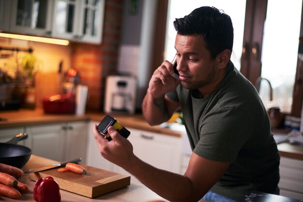 Человек разговаривает по мобильному телефону во время приготовления пищи