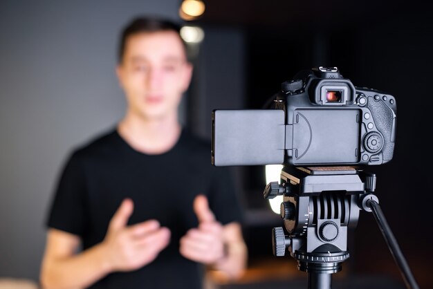 남자가 카메라를 향해 이야기하고 동영상 블로그에 자신을 기록합니다. 재택 근무. 젊은 콘텐츠 제작자
