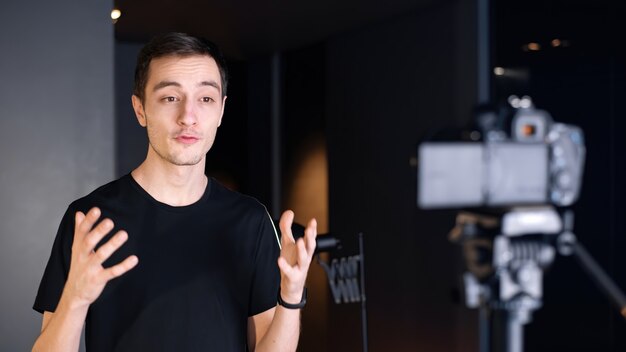 Man talking at the camera, recording himself in a vlog. Working from home. Young content creator