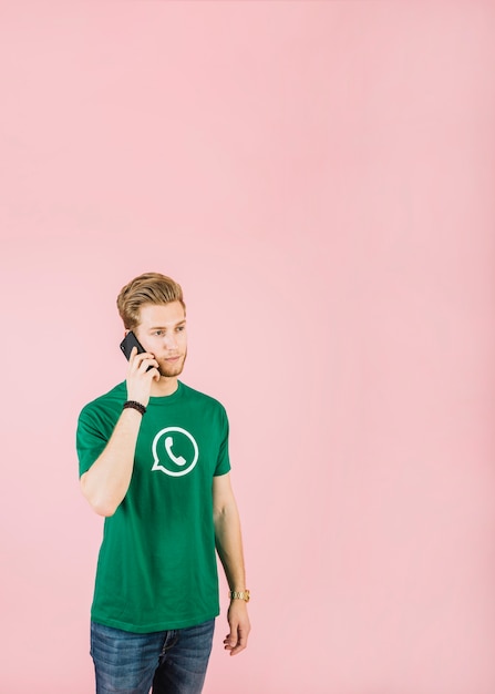 Free photo man talking on cellphone against pink background