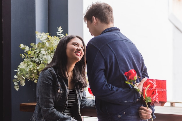 Foto gratuita l'uomo parlando con la sua ragazza e si nasconde sulla schiena un regalo e una rosa