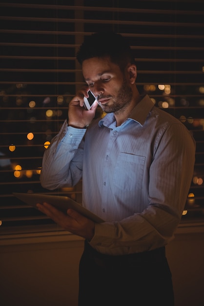 Free photo man talking on mobile phone while using digital tablet