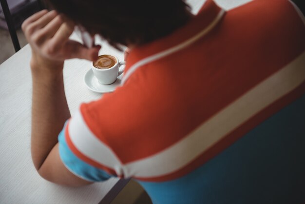 Man talking on mobile phone with coffee cup on table