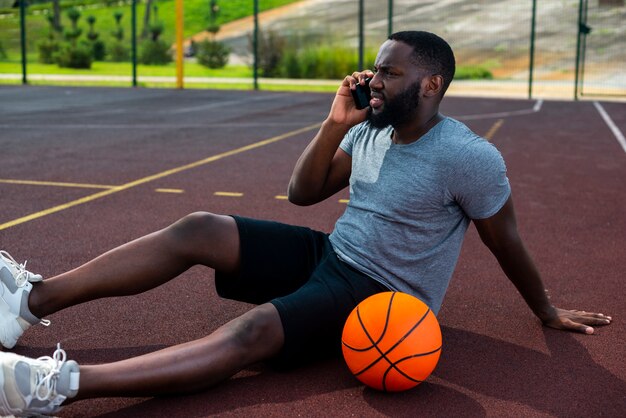 バスケットボールコートで電話で話している男性