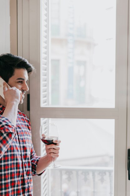 Человек разговаривает по телефону и с вином