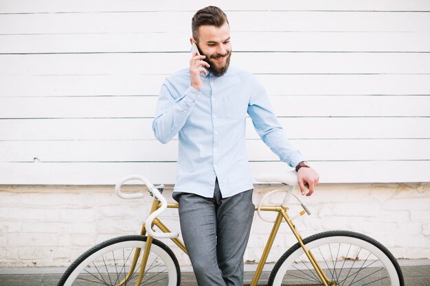 Man talking on phone near white wall