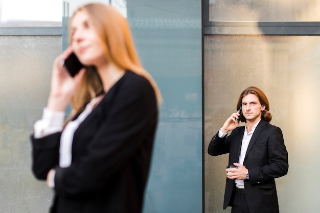 Man talking on the phone with a woman out of focus