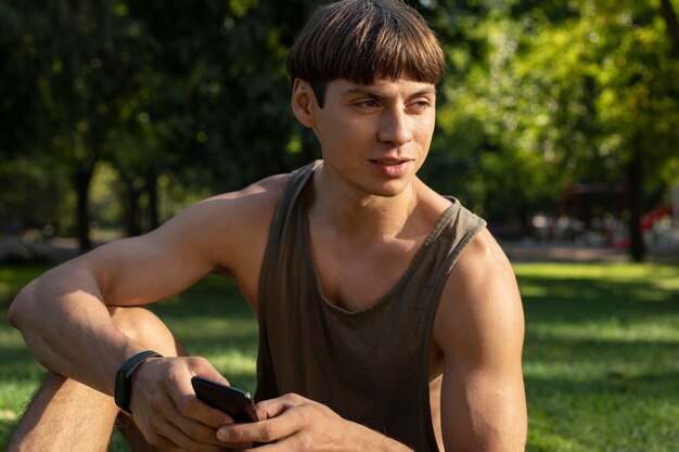 Man in tank top holding smartphone outdoors