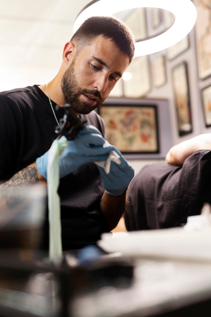 Free photo man tattooing with gloves medium shot