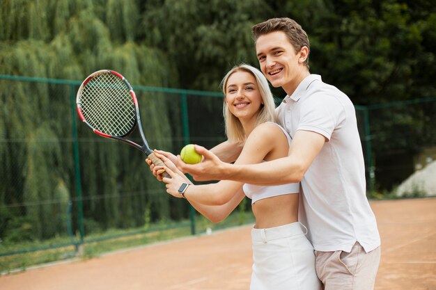 Man teaching woman to play tennis